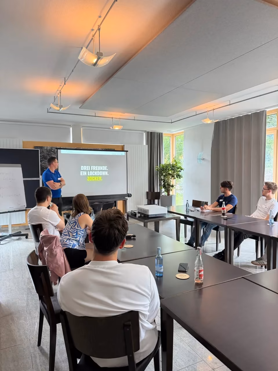 Ein Teilnehmer im blauen Poloshirt erzählt der Runde von seinem Projekt.